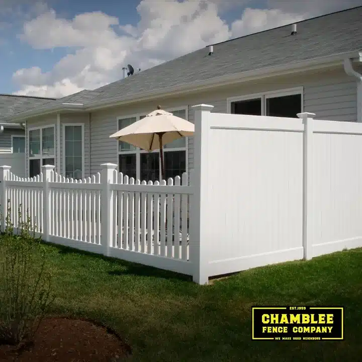 White vinyl privacy and picket fence enclosing a small backyard patio area
