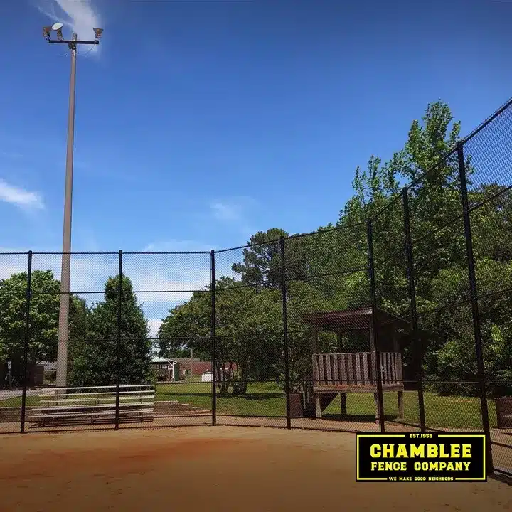 Tall black chain link fence enclosing a baseball field with bleachers and a wooden viewing deck, installed by Chamblee Fence Company in Atlanta, Georgia