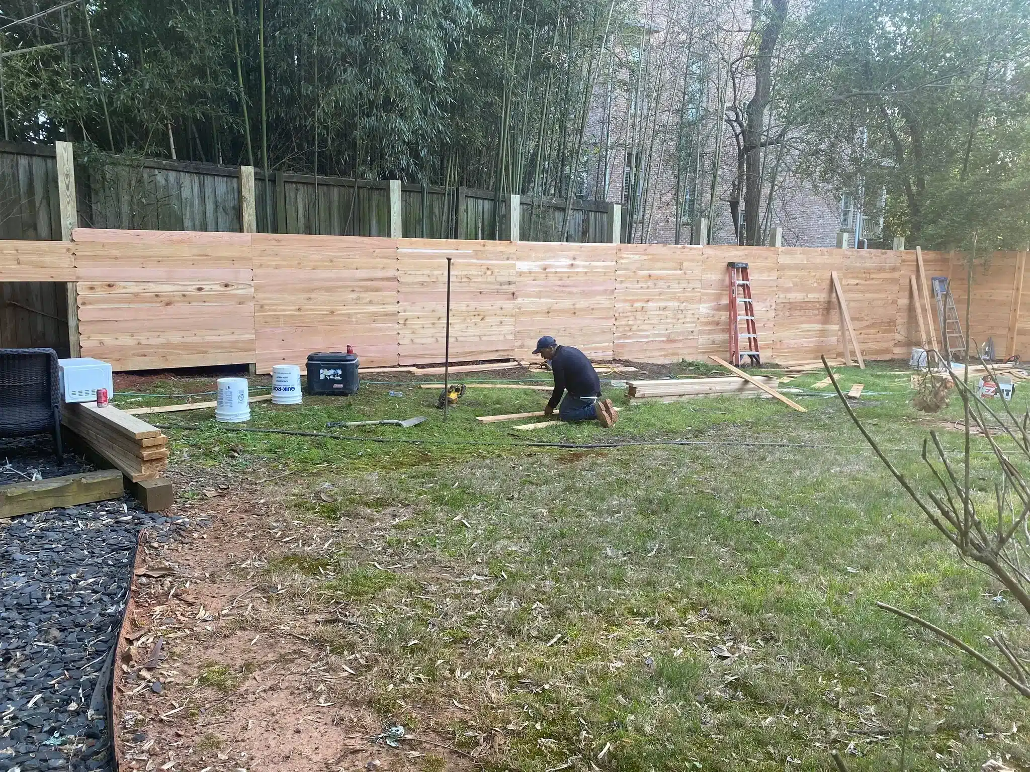 Fence installer setting a post in concrete during a residential fence installation in a suburban yard.”