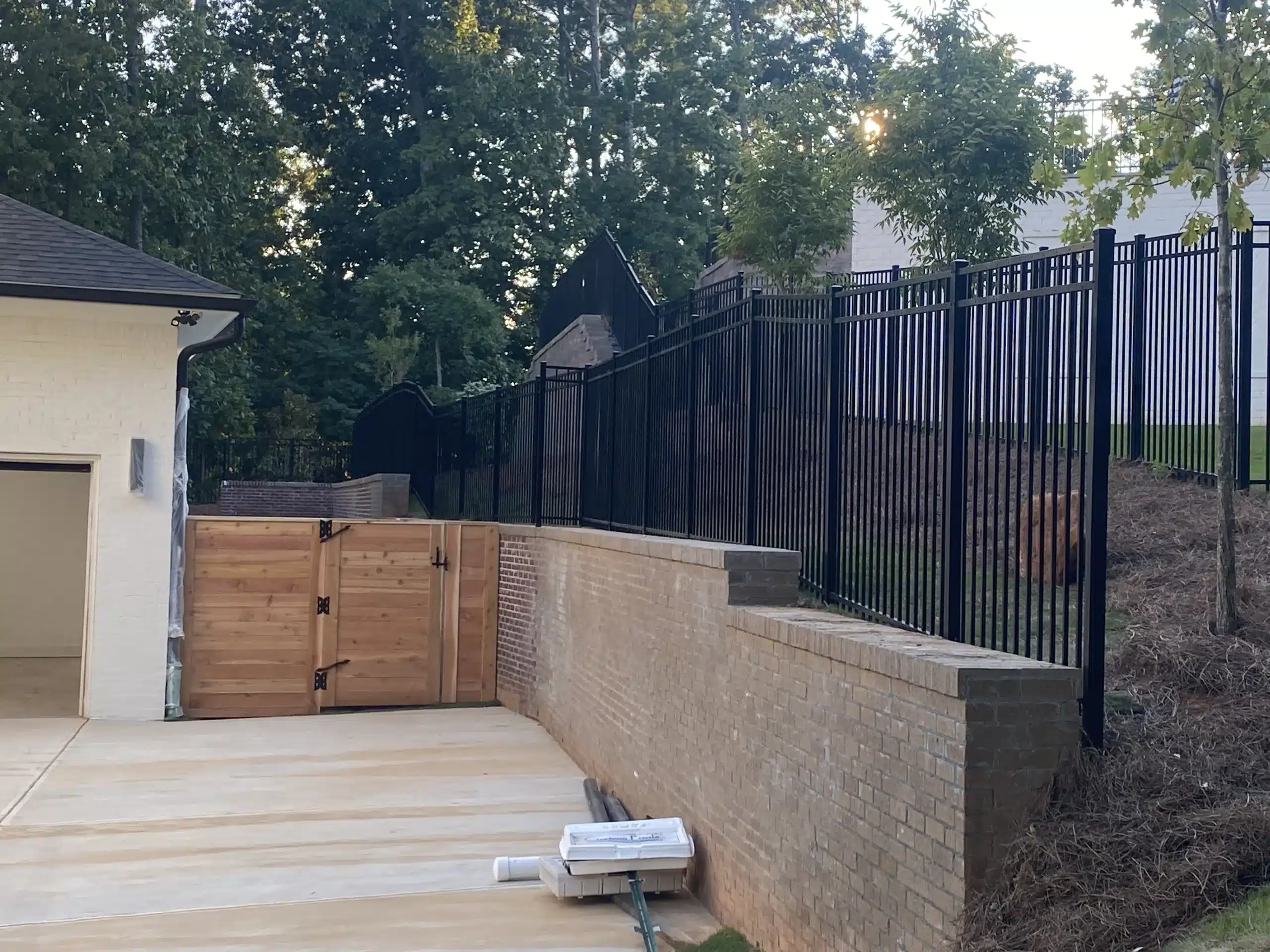 Black aluminum fence installed on a brick retaining wall at a residential Atlanta home, illustrating modern fencing costs and design options for 2026.