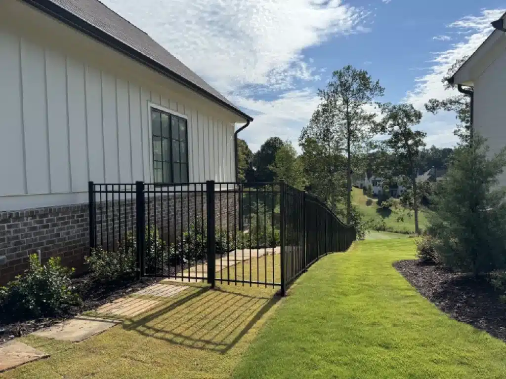 Black aluminum fence and gate installed along a sloped residential side yard in Marietta, GA