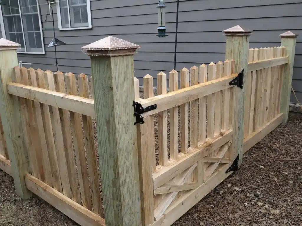 Wood picket enclosure with matching gate installed around backyard equipment in Kennesaw, GA