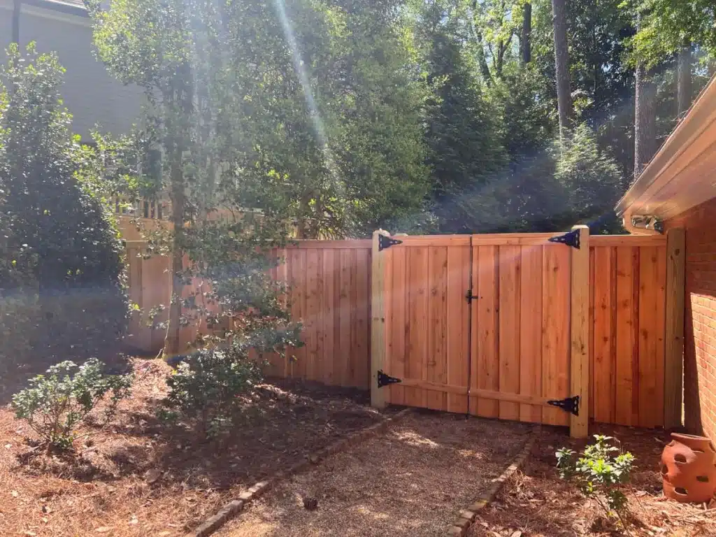 Wood privacy fence and gate installed near a home walkway
