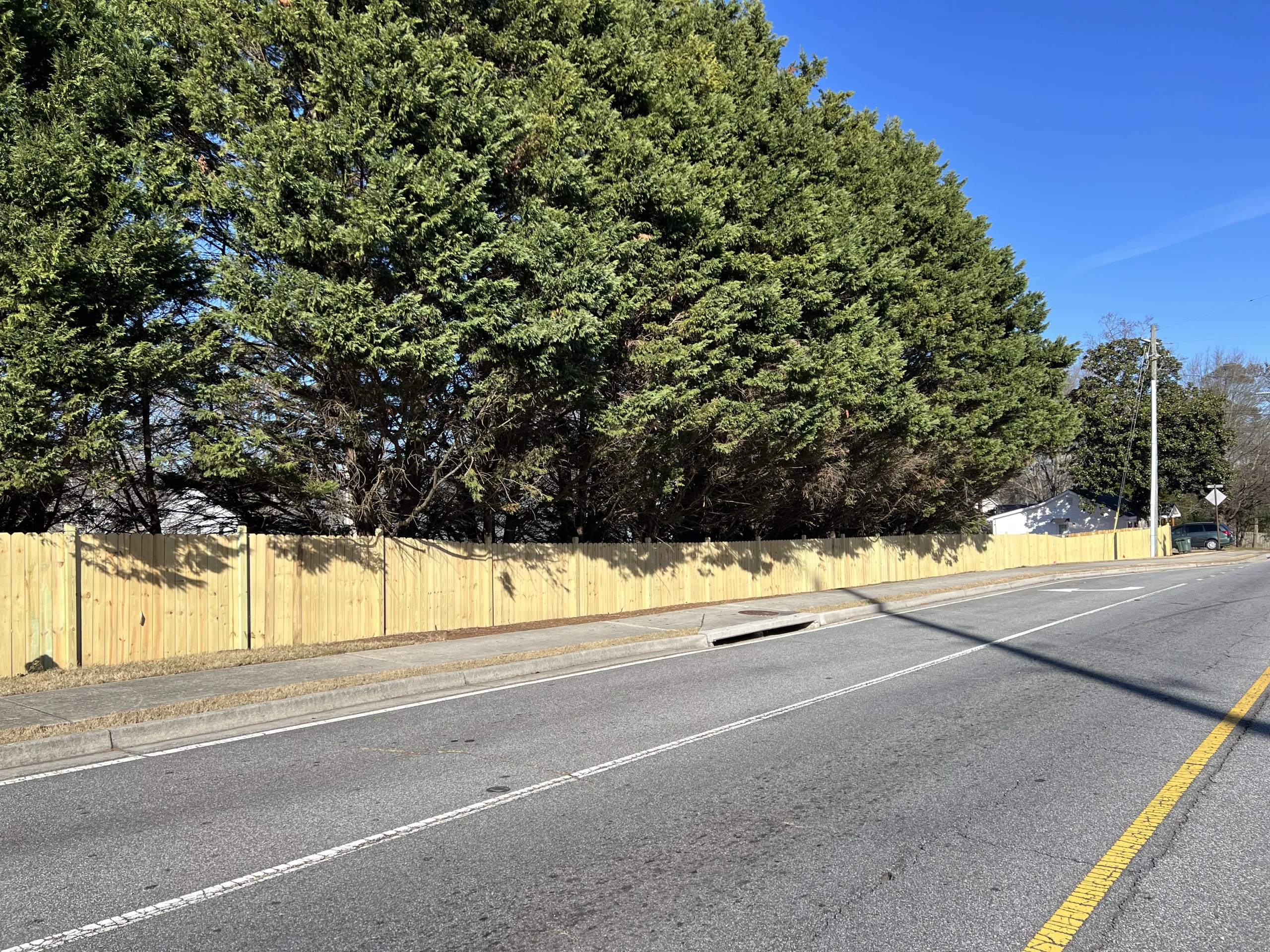 Wood privacy fence installed along tree-lined property showing fence options for wooded backyard in Kennesaw with dense tree coverage and root-heavy terrain.